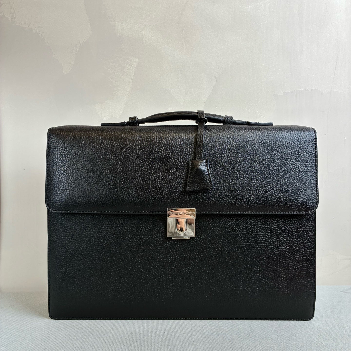 Ermenegildo Zegna This is the Zegna men's briefcase, made of embossed cowhide leather, featuring a lock buckle flap design, primarily targeting business communication.